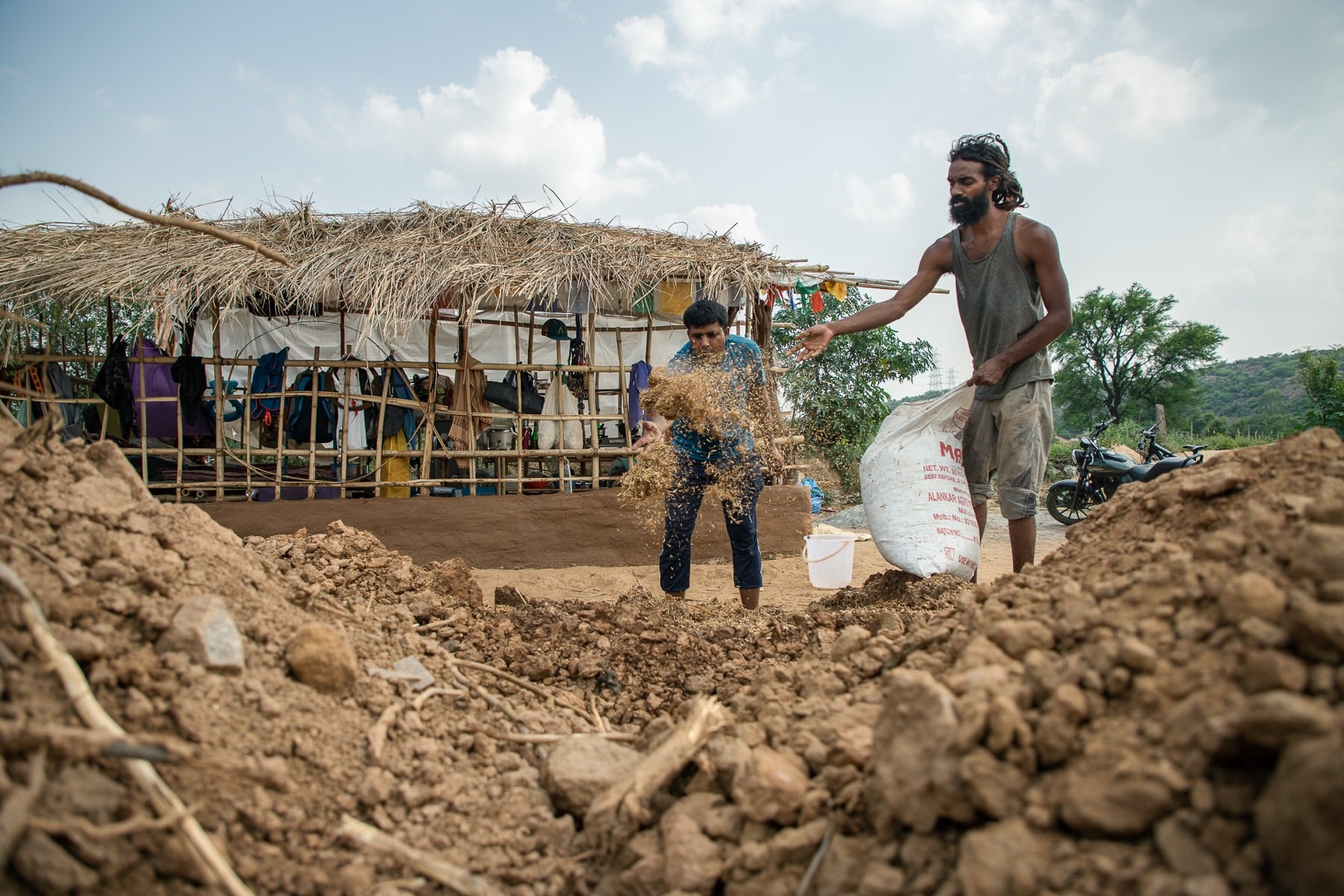 Earthbag walls beside a thatched shelter